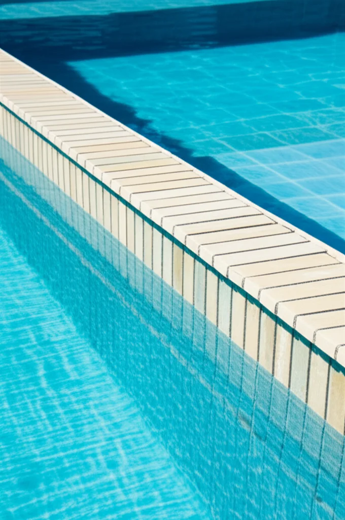 Detailed close-up showcasing the precise construction of an infinity edge pool's weir, demonstrating the continuous flow