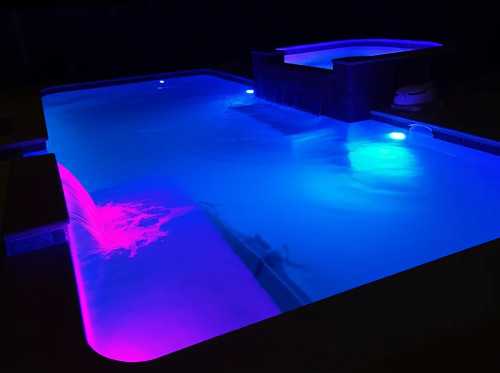 Ambient nighttime scene of a Fort Worth pool featuring color-changing LED underwater lights illuminating the water, high